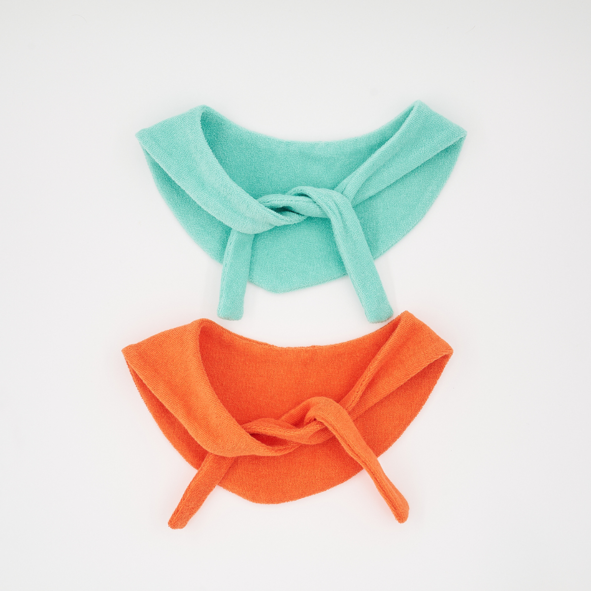 Flat lay of Colorful Daily Series pet bandanas in green and orange on white background