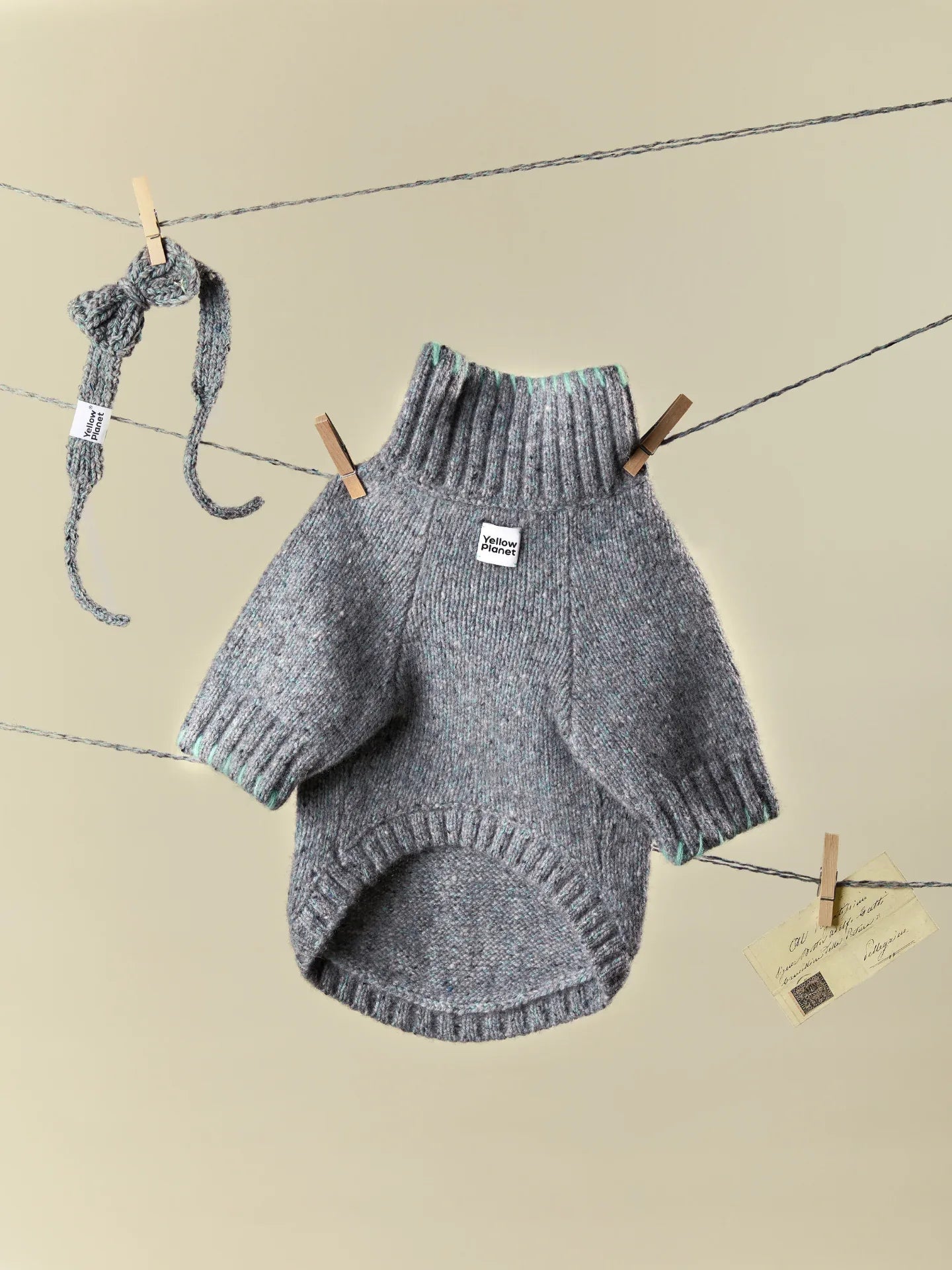 Main product view of the Sage Tweed alpaca-wool blend dog sweater with matching knitted bow tie hanging on a clothesline.