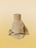 Main studio shot of the Oat Tweed alpaca-wool dog sweater, featuring a thick ribbed turtleneck and natural flecked yarn.