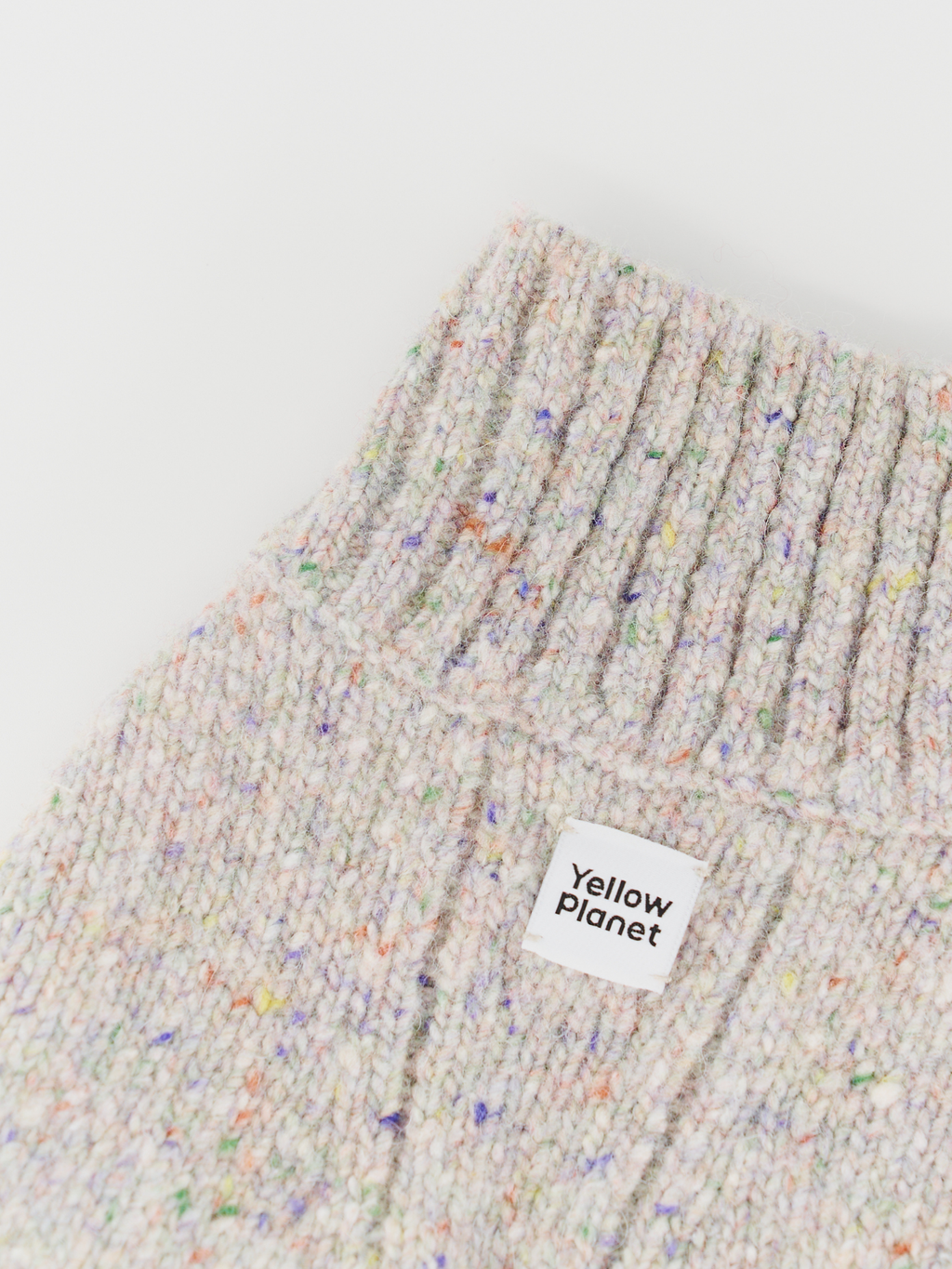 Close-up of the Confetti Cream sweater collar and chest, clearly showing the colorful confetti flecks, dense knit, and the Yellow Planet logo.