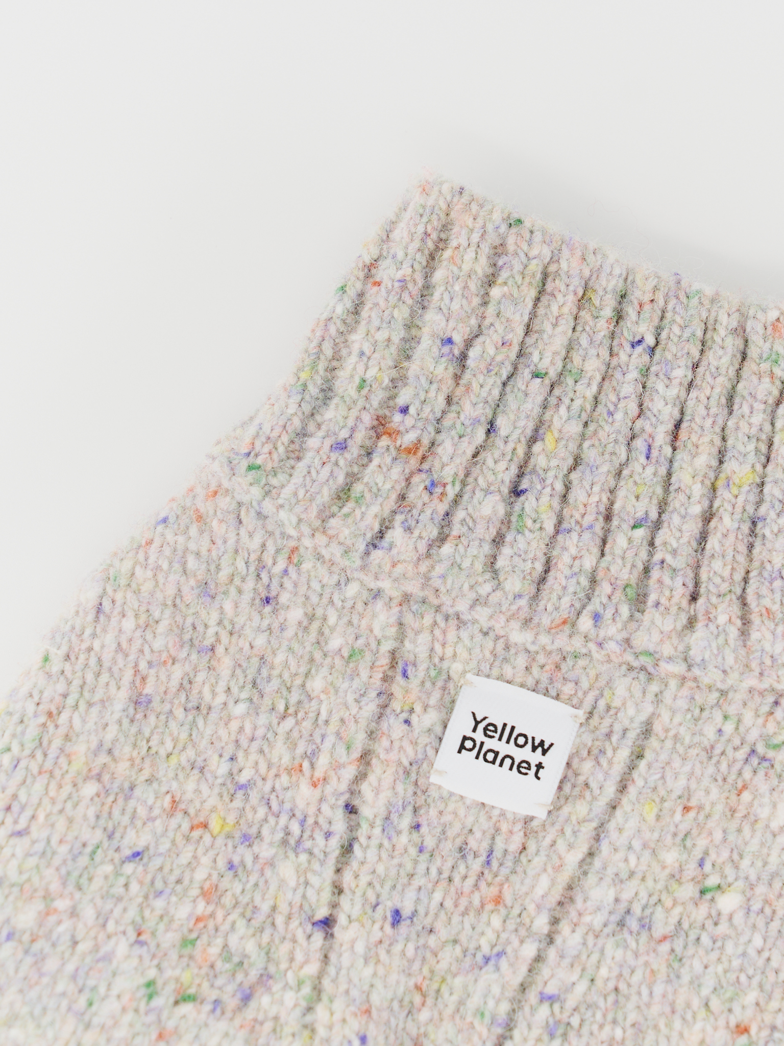 Close-up of the Confetti Cream sweater collar and chest, clearly showing the colorful confetti flecks, dense knit, and the Yellow Planet logo.