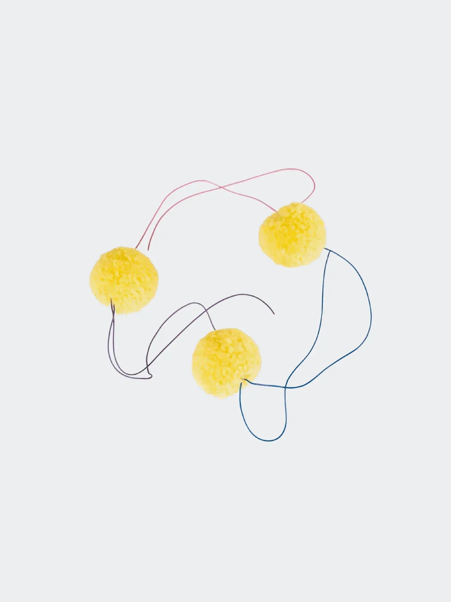 Close-up of four bright yellow detachable pom-poms with strings, illustrating the customizable feature of the beanie.