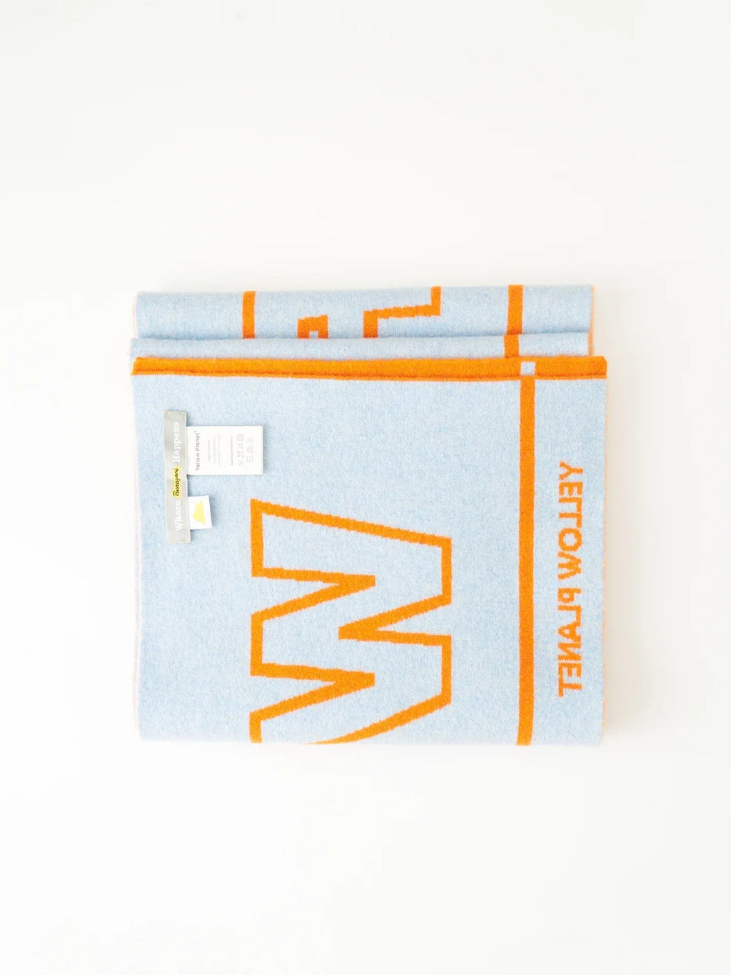 A lifestyle arrangement of stacked "WOOF" theme scarves with various autumnal props and a "Yellow Press" book.