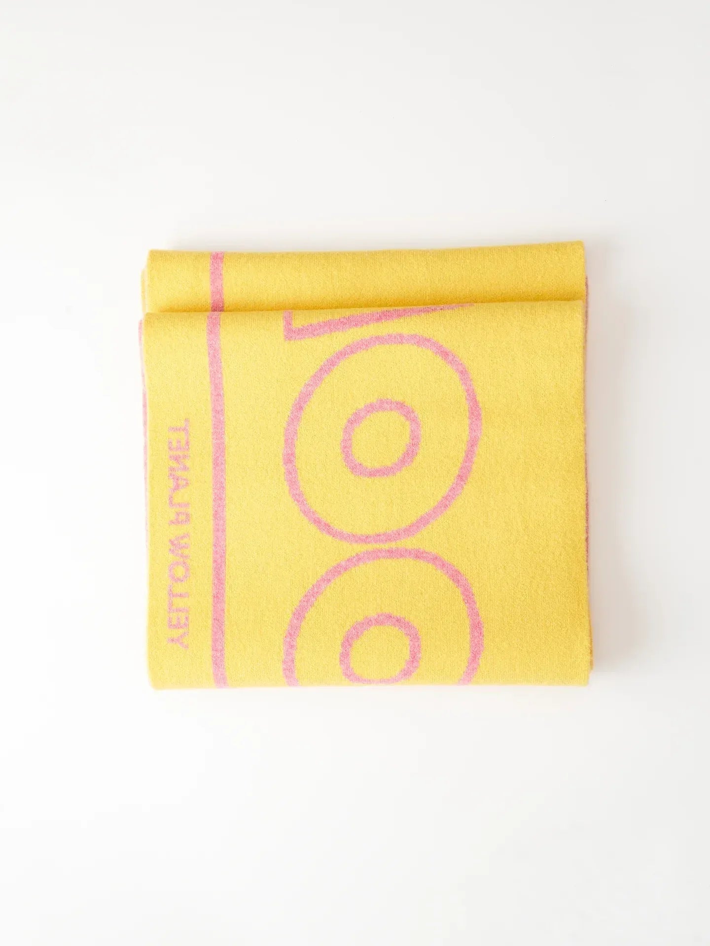 A creative lifestyle stack of the "WOOF" scarf collection on top of a "Yellow Press" book with autumnal props.