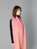 Side view of a woman modeling the DOG-Sophy "WOOF" theme reversible wool scarf in a vibrant pink and yellow colorway.