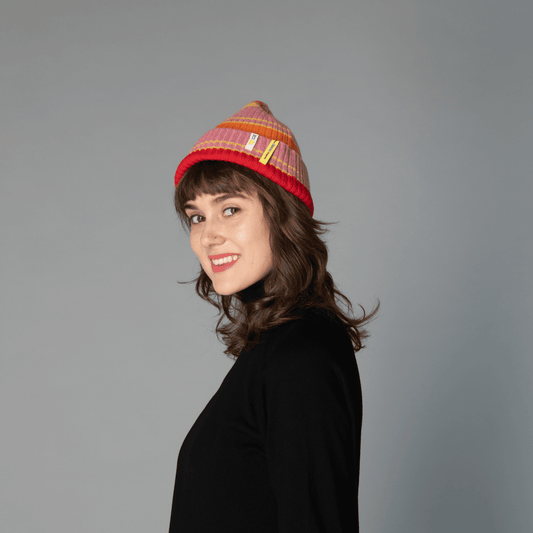 "Female model wearing a pink Color Heal Series Merino Wool beanie with playful pom-pom, looking at the camera.