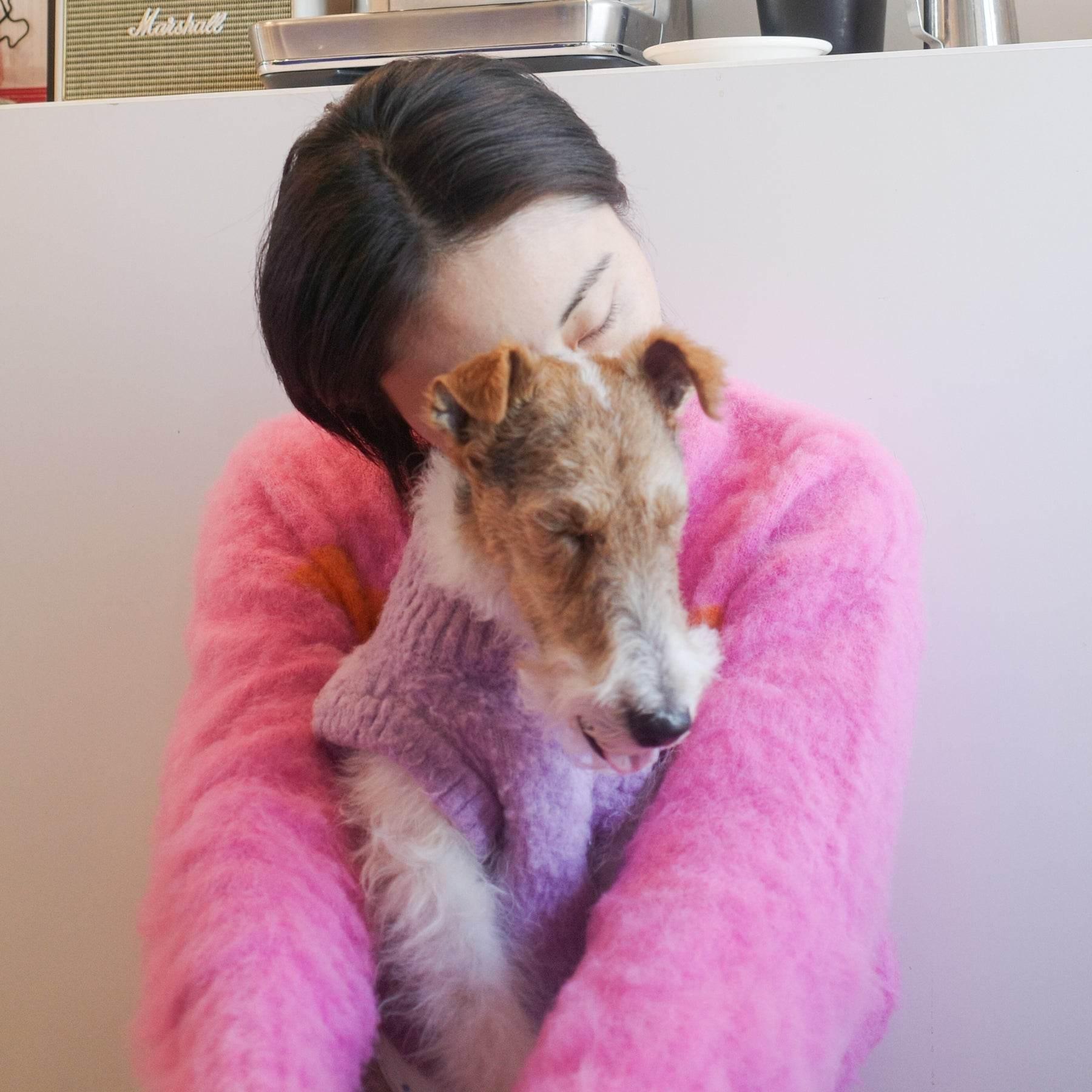 A woman in the Pink-Orange color-blocked fuzzy sweater embracing her pet, showcasing the cozy fit and vibrant hues.