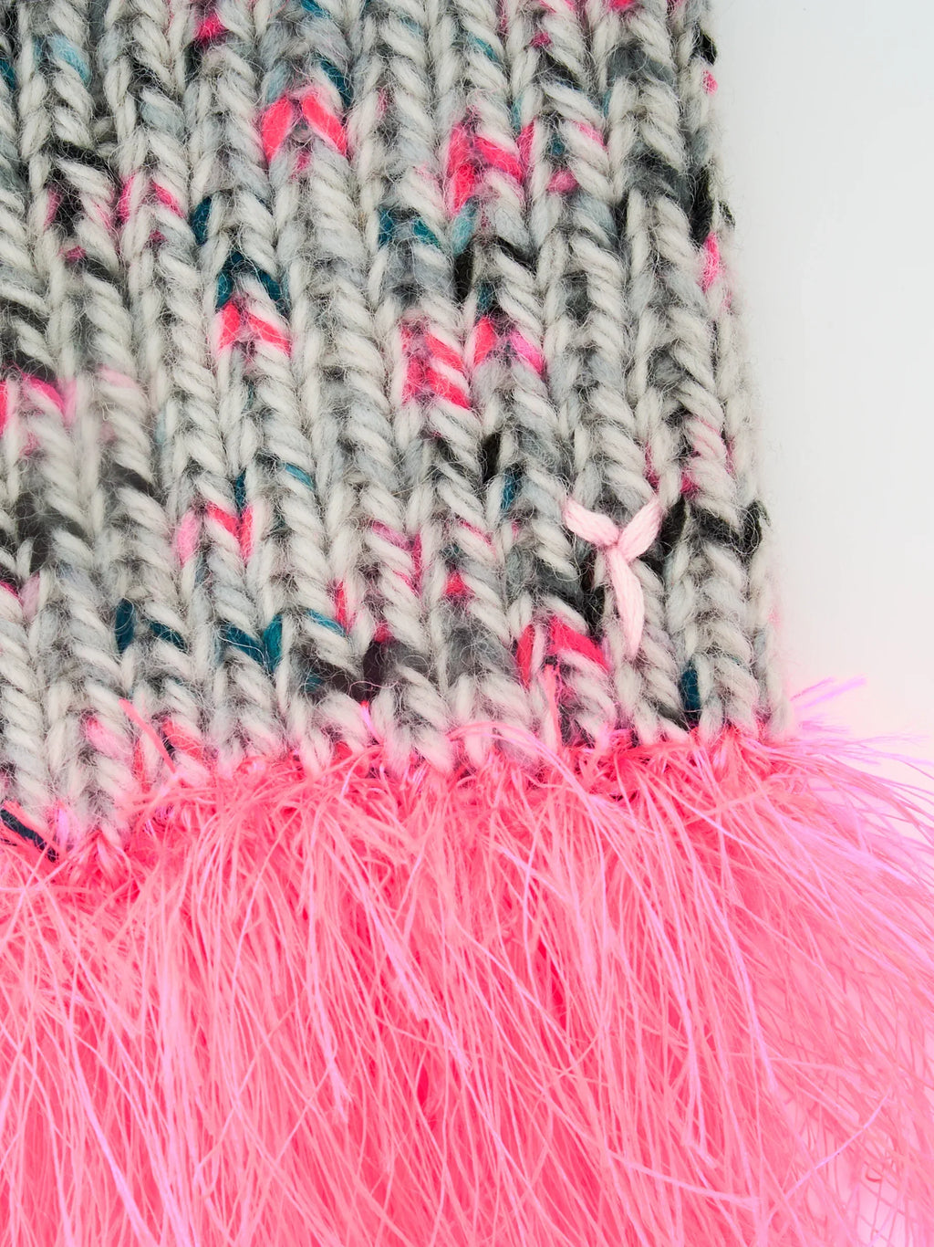 Close-up of the textured gray speckled wool knit and the fluffy neon pink sea anemone yarn fringe detail.