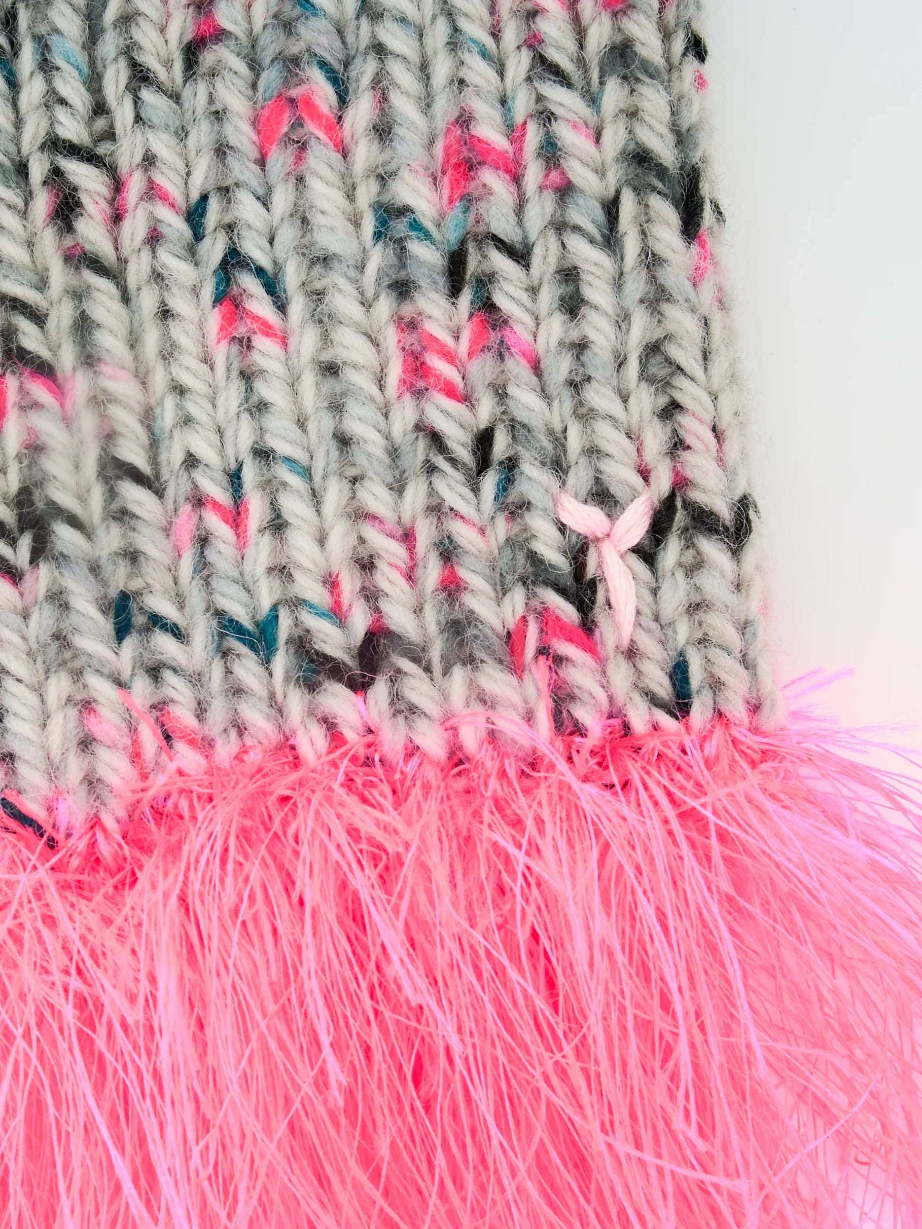 Close-up of the textured gray speckled wool knit and the fluffy neon pink sea anemone yarn fringe detail.