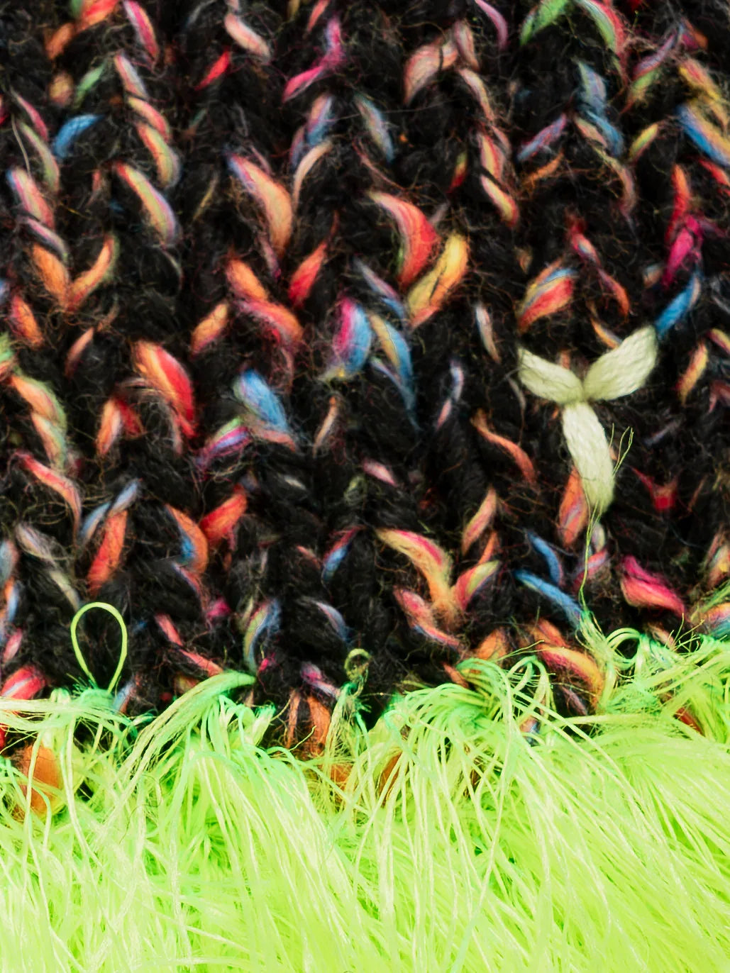 Close-up of the vibrant HANABI multi-color speckled wool knit and the electric neon green sea anemone yarn fringe.