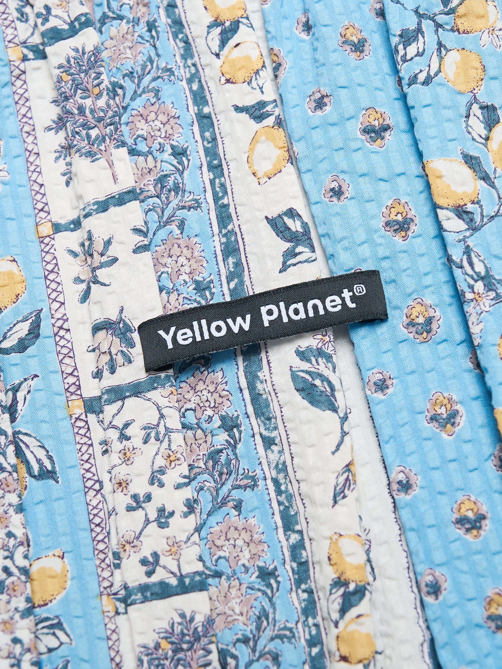 Close-up of the Colorful Daily Nature's Verse Gentle Wave Snood in Limoncello showing the printed fabric and Yellow Planet label.