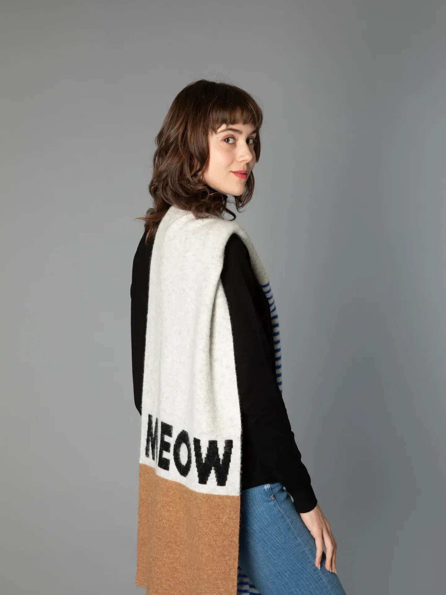 Side profile of a woman wearing the long "MEOW" colorblock scarf, highlighting the bold black typography.
