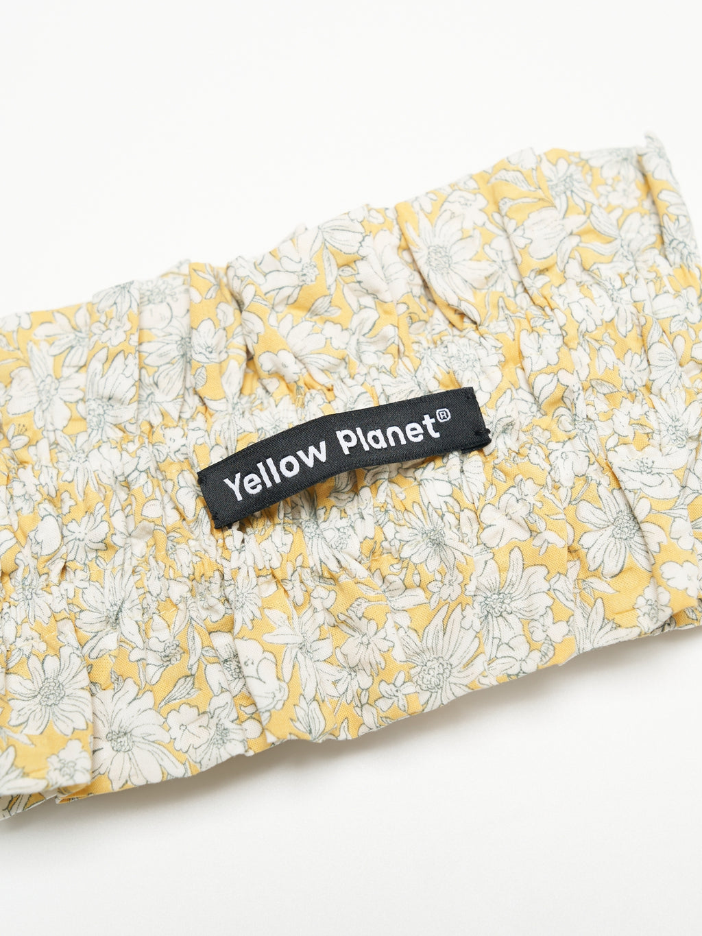 Close-up of the Daisy printed cotton fabric and Yellow Planet label on the Nature's Verse Bow Neckpiece.