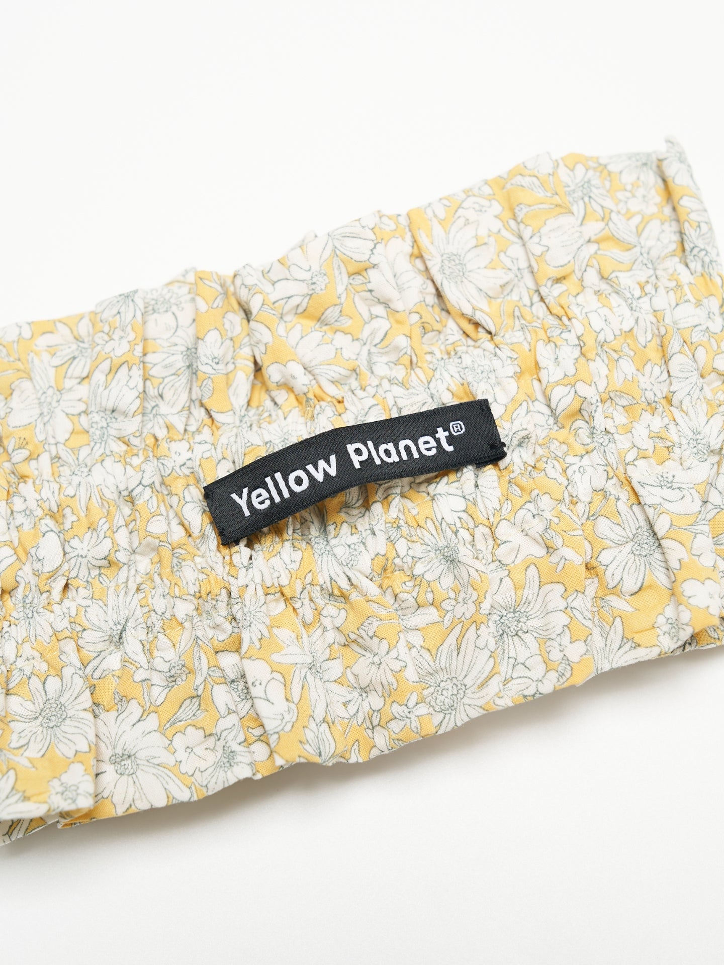 Close-up of the Daisy printed cotton fabric and Yellow Planet label on the Nature's Verse Bow Neckpiece.