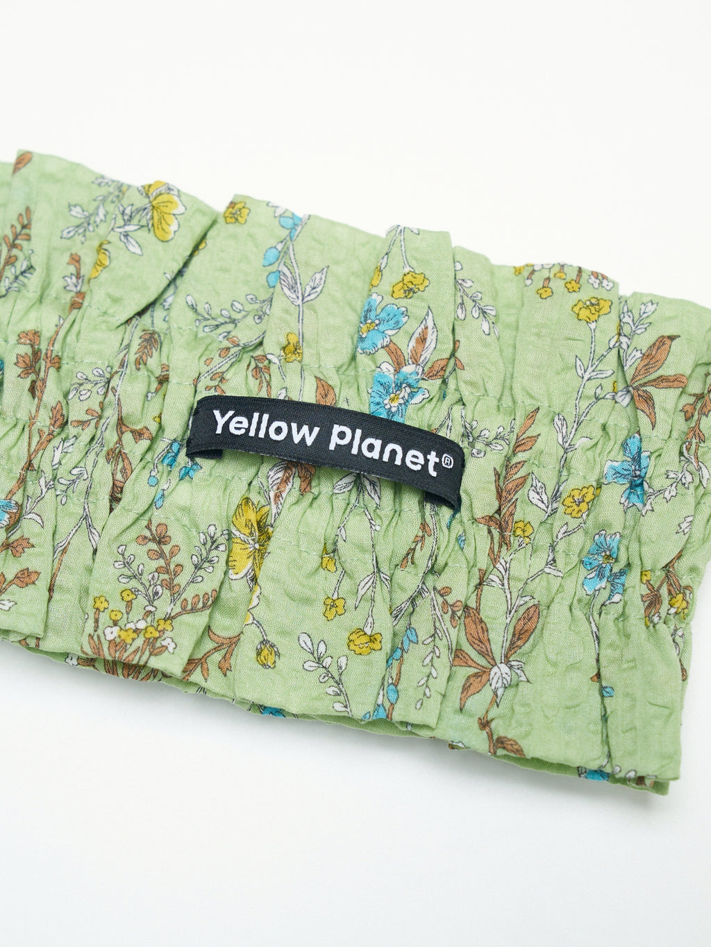 Close-up of the Forest Green printed cotton fabric and Yellow Planet label on the Nature's Verse Bow Neckpiece.