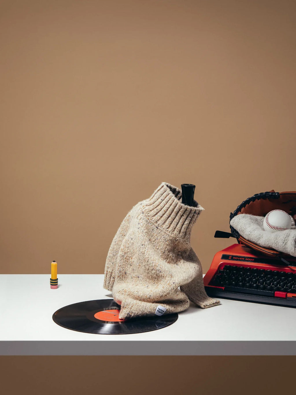 The Oat Tweed alpaca wool sweater styled in a vintage setting with a typewriter and vinyl record, emphasizing an elegant lifestyle.