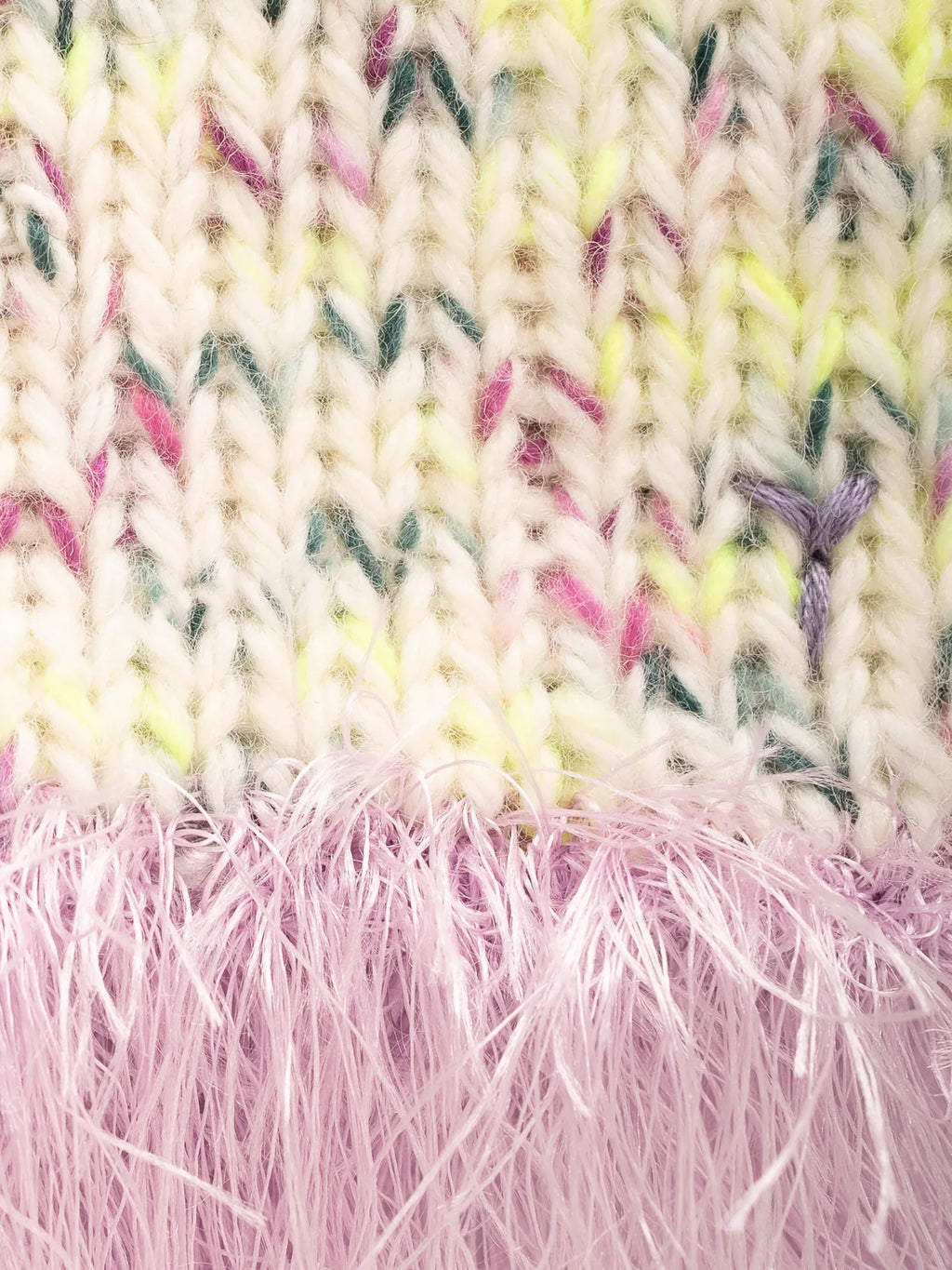 Close-up detail of the chunky off-white speckled wool knit and the soft, fluffy lavender purple fringe tassels.