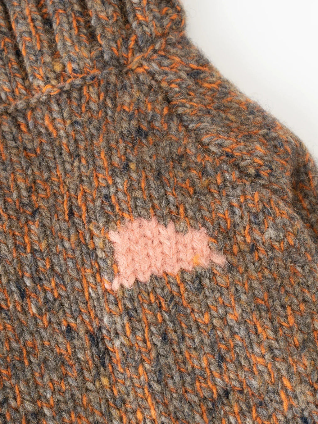 Extreme close-up of the delicate pink intarsia knit graphic on the Rust Tweed alpaca-wool blend fabric.