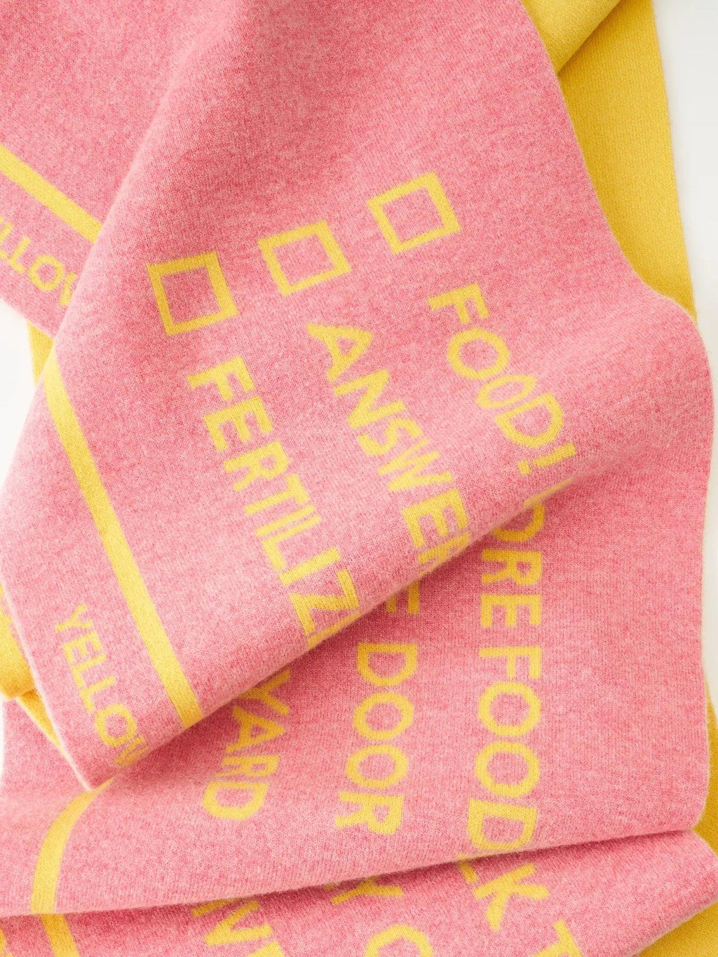 Close-up of the pink side of the reversible scarf showing yellow "WOOF" typography and dog-themed checkbox design.