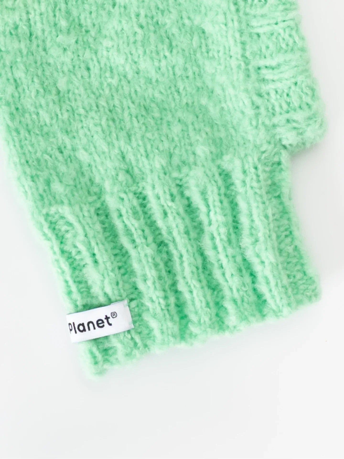 Detailed shot of the flexible ribbed neck and "Planet" brand label on the mint green fuzzy wool pet snood.