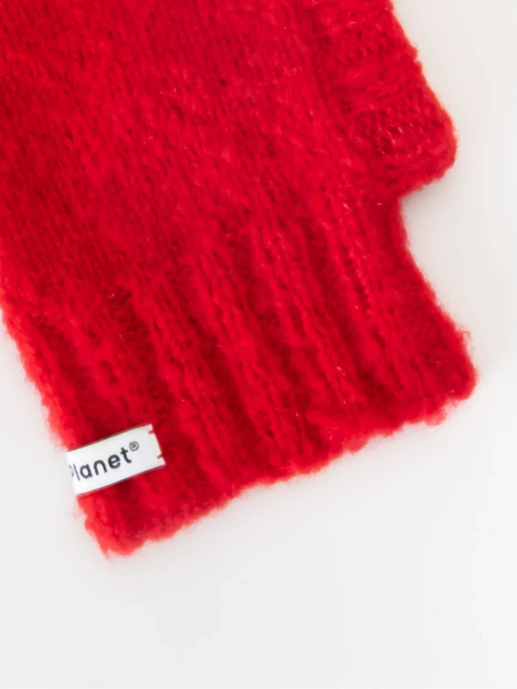 Detailed shot of the comfortable ribbed neck and "Yellow Planet" woven brand label on the red knitted beanie.