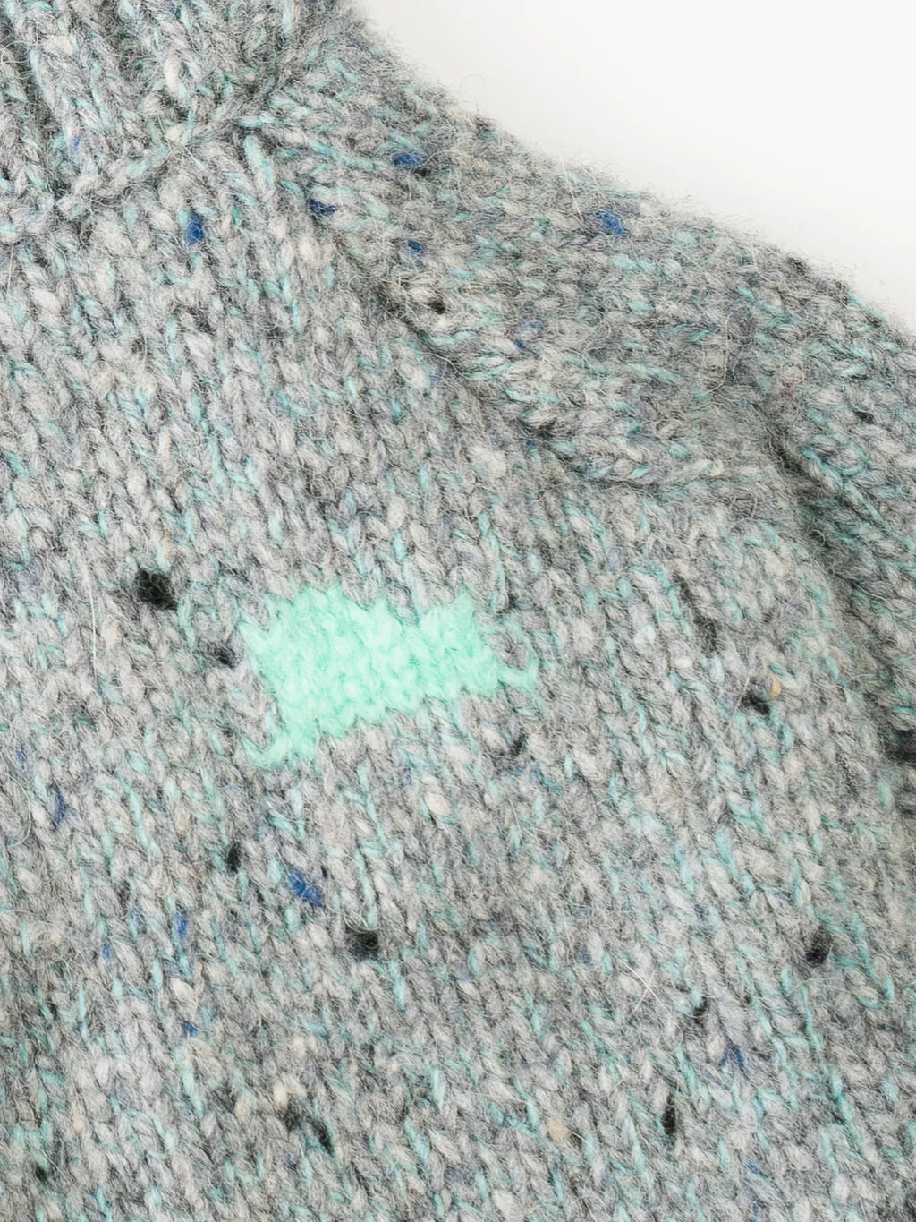 Macro shot of the Sage Tweed yarn texture, showing blue and black flecks in the alpaca-wool blend.