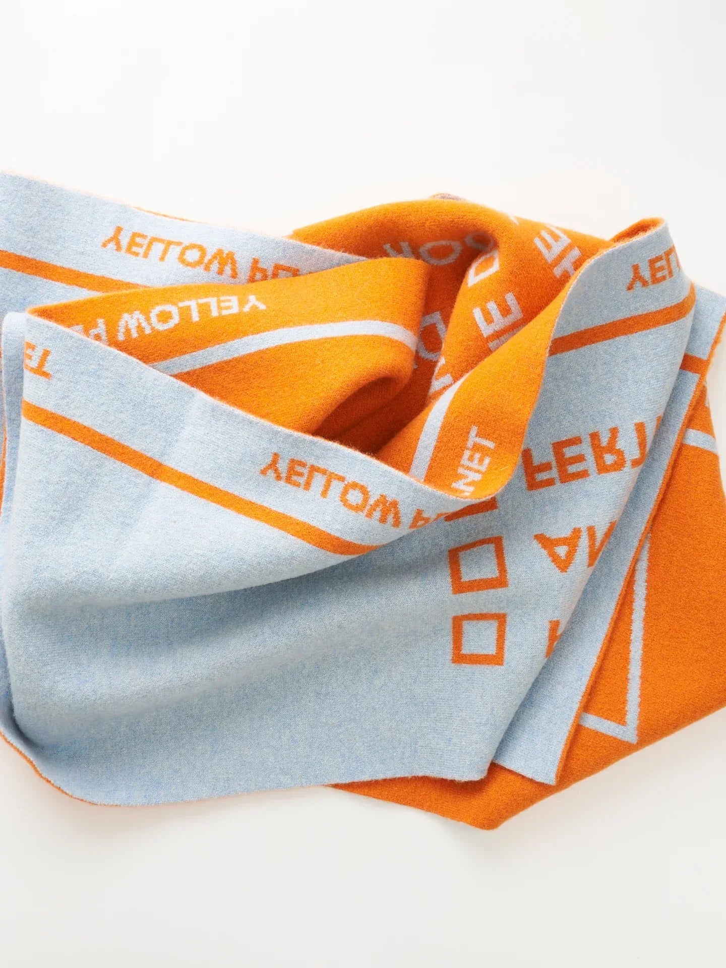A flat-lay studio shot of the folded "WOOF" scarf, highlighting the high-contrast sky blue and orange color palette.