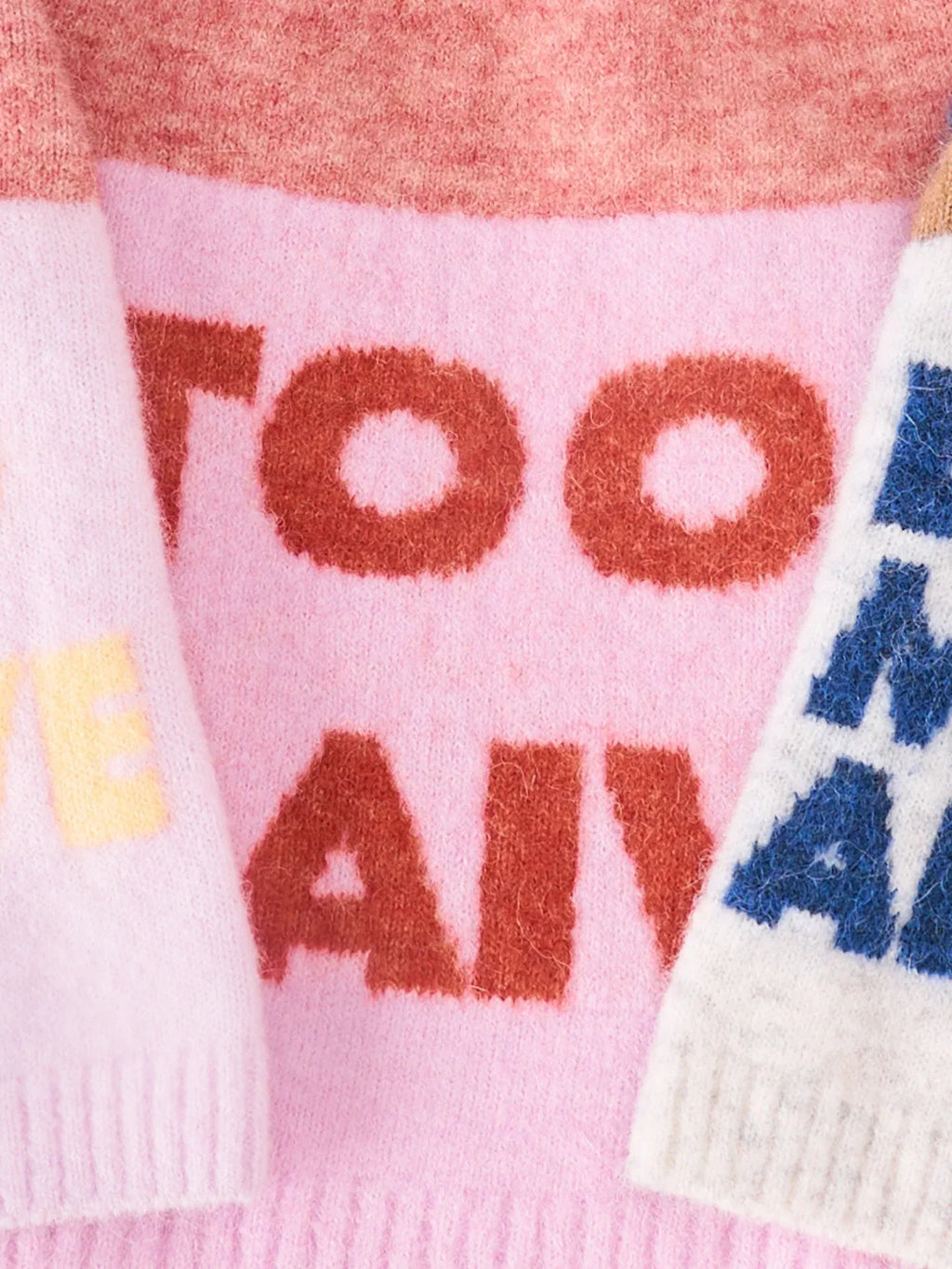 Close-up of the "TOO NAIVE" bold typography on the pink and coral red alpaca wool knit vest.