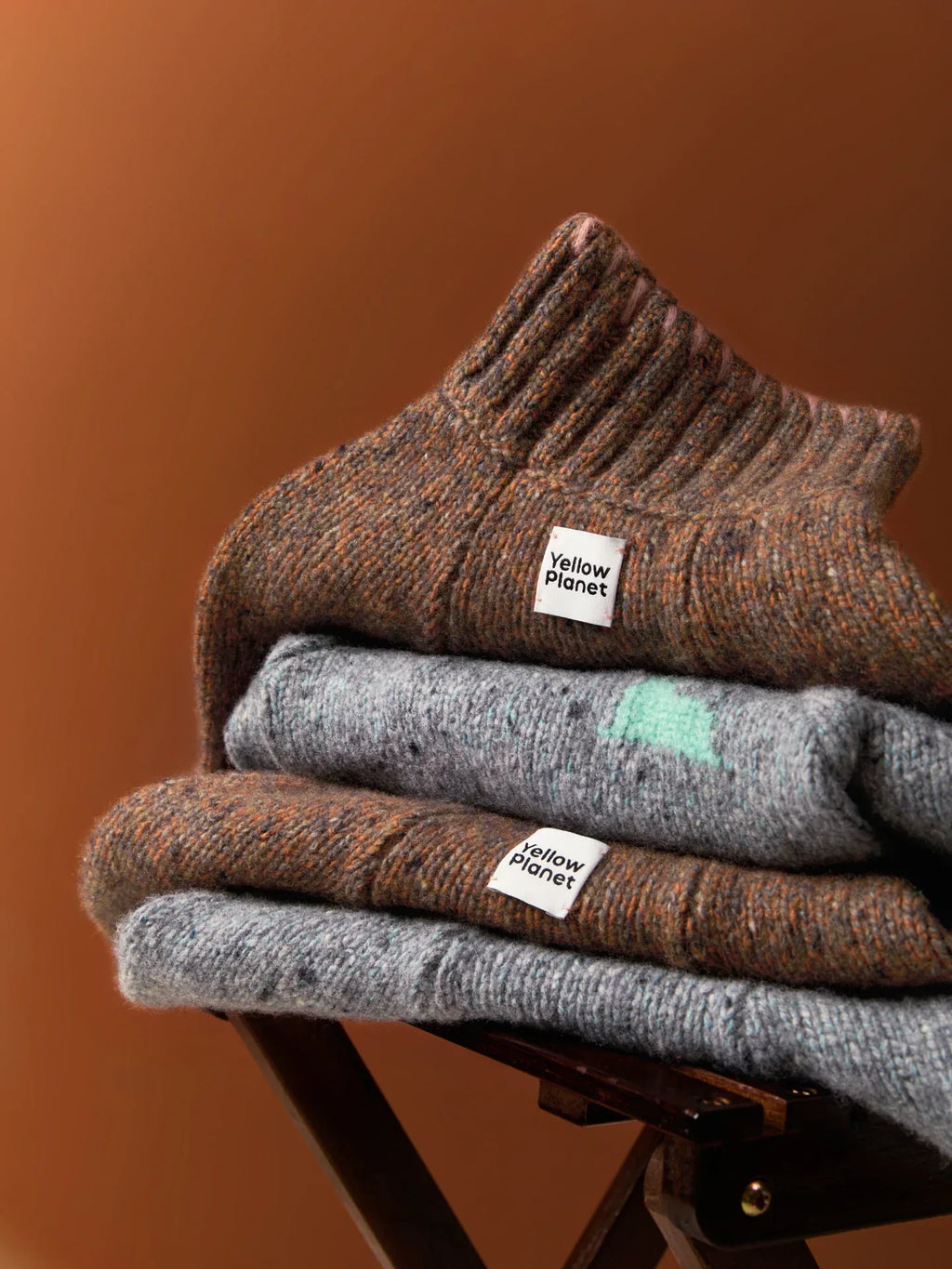 A stack of Funky Gentle Dog Series sweaters in Earth Brown and Sage Tweed, highlighting the thick ribbed necklines.