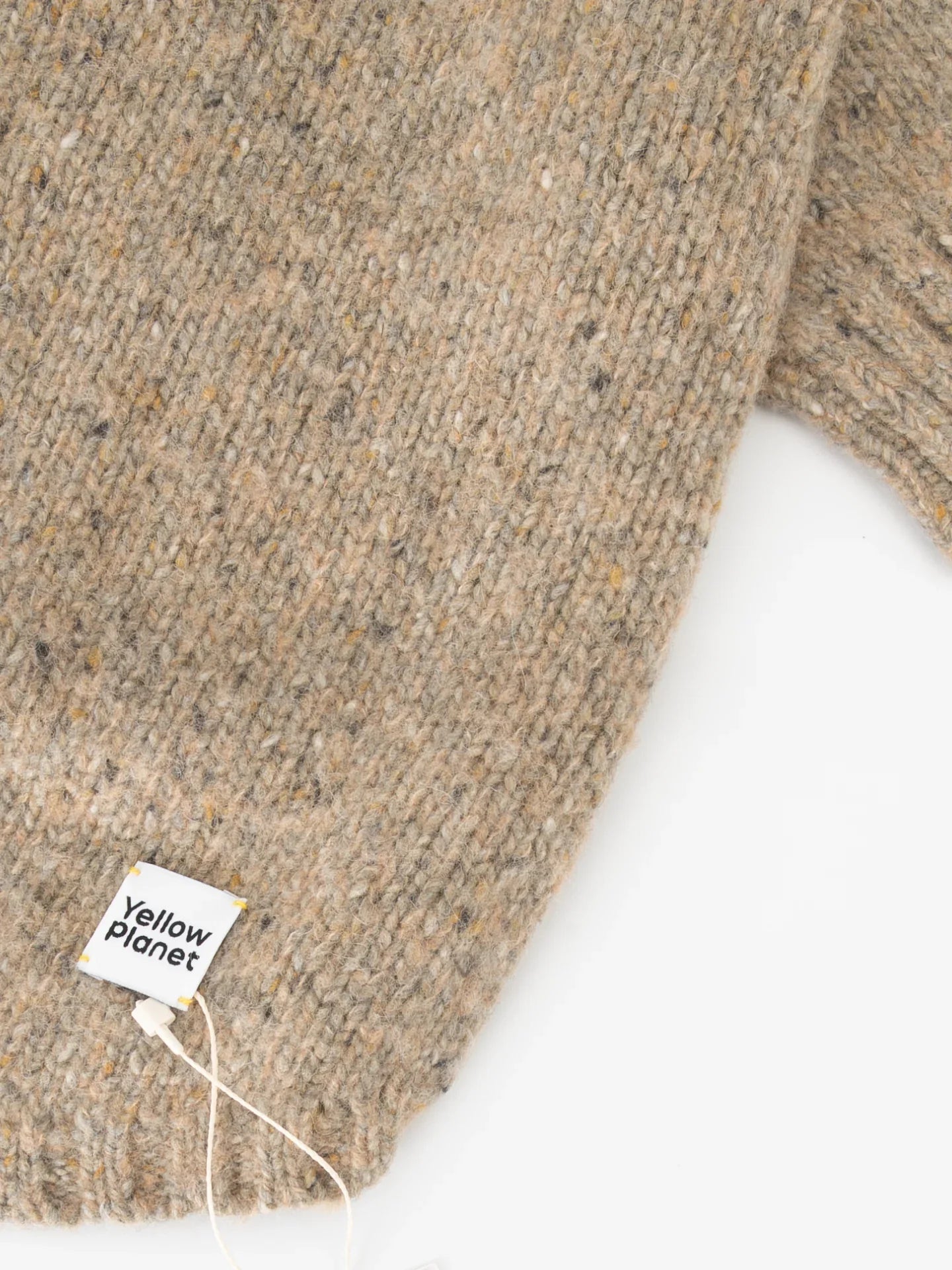 Detail shot of the "Yellow Planet" woven brand label on the hem of the Walnut Tweed alpaca wool sweater.